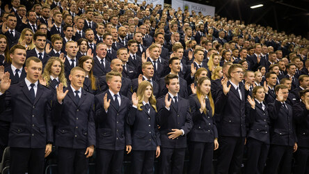 Das Foto zeigt eine große Gruppe junger Frauen und Männer in ihren Uniformen für festliche Anlässe. Sie heben alle ihre rechte Hand. Sie sprechen den Diensteid.