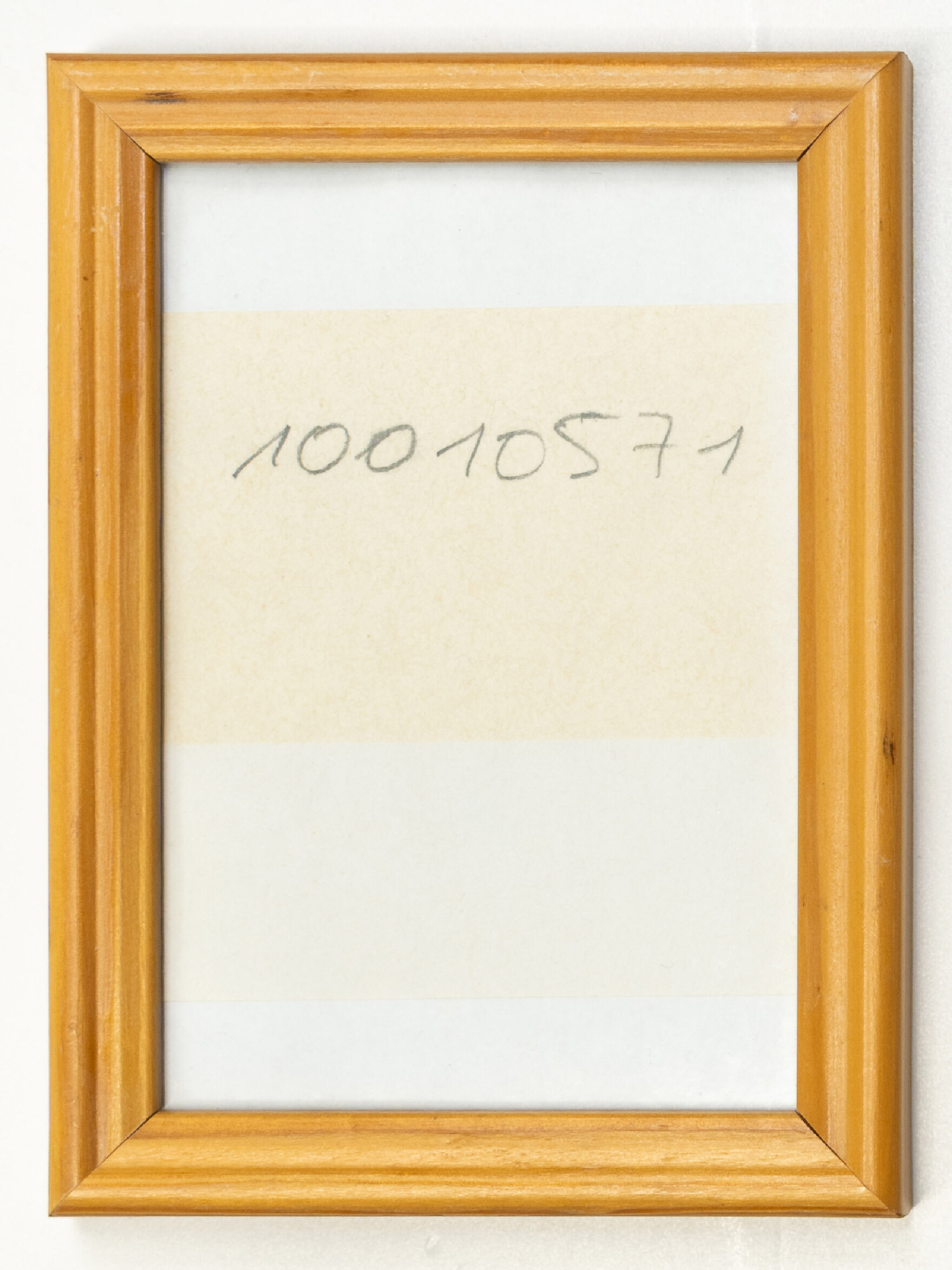 In einem braunen Bilderrahmen befindet sich ein Zettel mit der Aufschrift: »10010571«. 