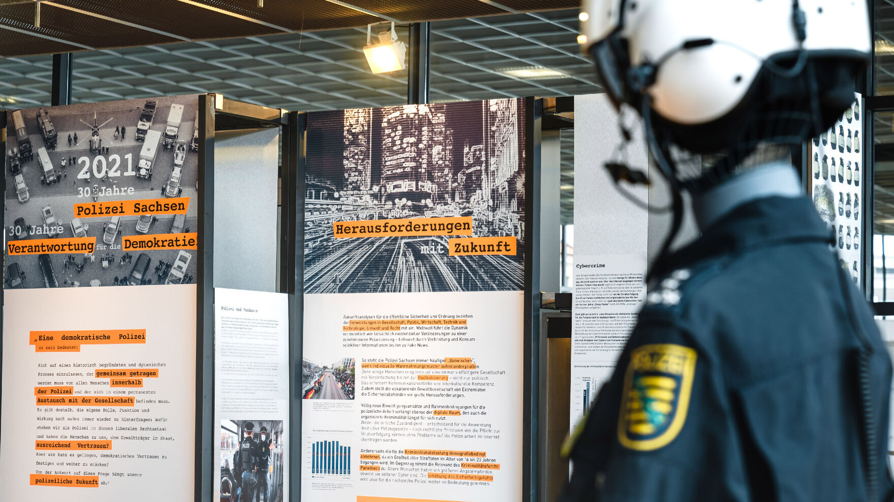 Das Foto zeigt Schautafeln der Ausstellung mit Bildern und Texten. Auf einer Tafel steht: »2021 – 30 Jahre Polizei Sachsen – 30 Jahre Verantwortung für die Demokratie«. Rechts ist unscharf eine Polizeiuniform unscharf zu sehen.
